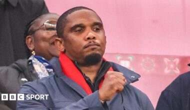 Samuel Eto'o raises his right fist while seen in the stands at a football match