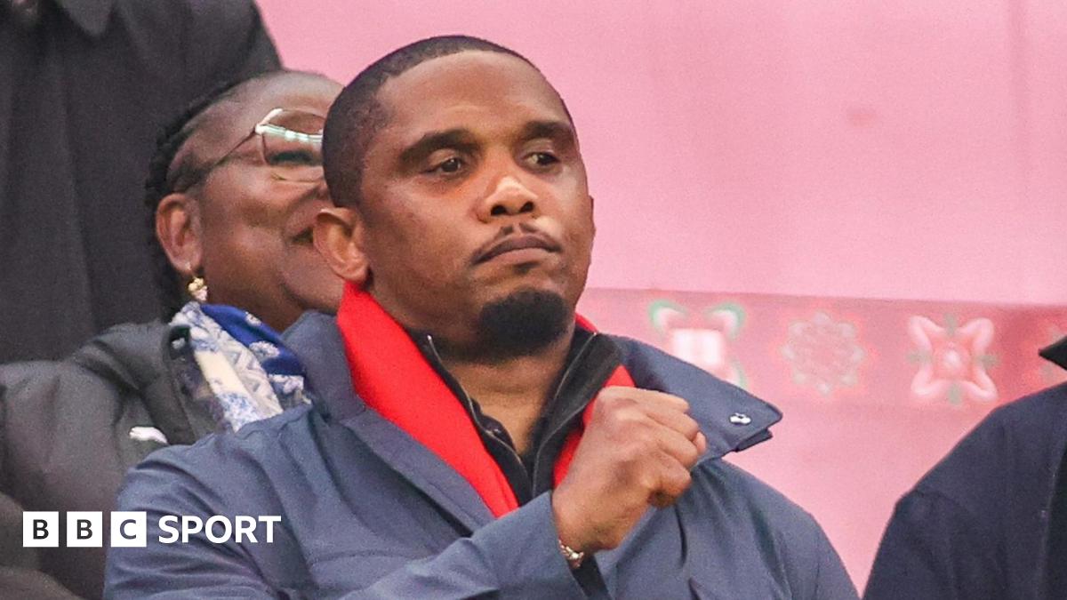 Samuel Eto'o raises his right fist while seen in the stands at a football match