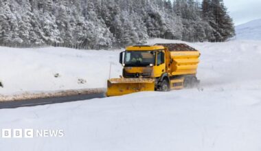 A bright yellow snowplough makes its way through heavy snowfall on the A87 road between Inverness and Ullapool