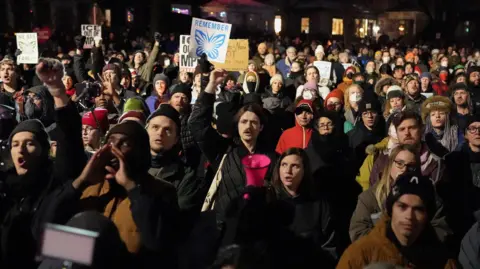 REUTERS/Tim Evans In the dark, a photo taken from above shows a vast group of peopel wearing heavy coats and carrying signs. 
