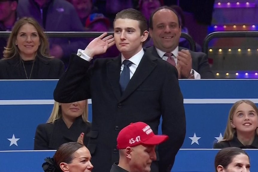 Barron Trump stands up, has his hand over ears