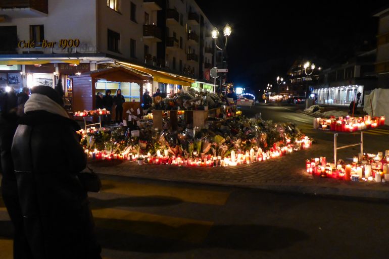 A person looks at a makeshift memorial following a fire at "Le Constellation" bar during New Year's Eve celebrations, killing 40 people and injuring 119, in the Alpine ski resort town of Crans-Montana, on January 3, 2026.