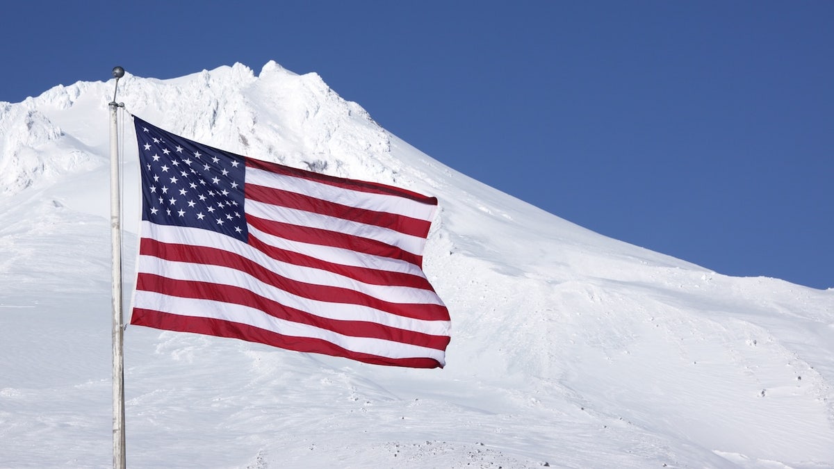 american flag swaying in front of mountain