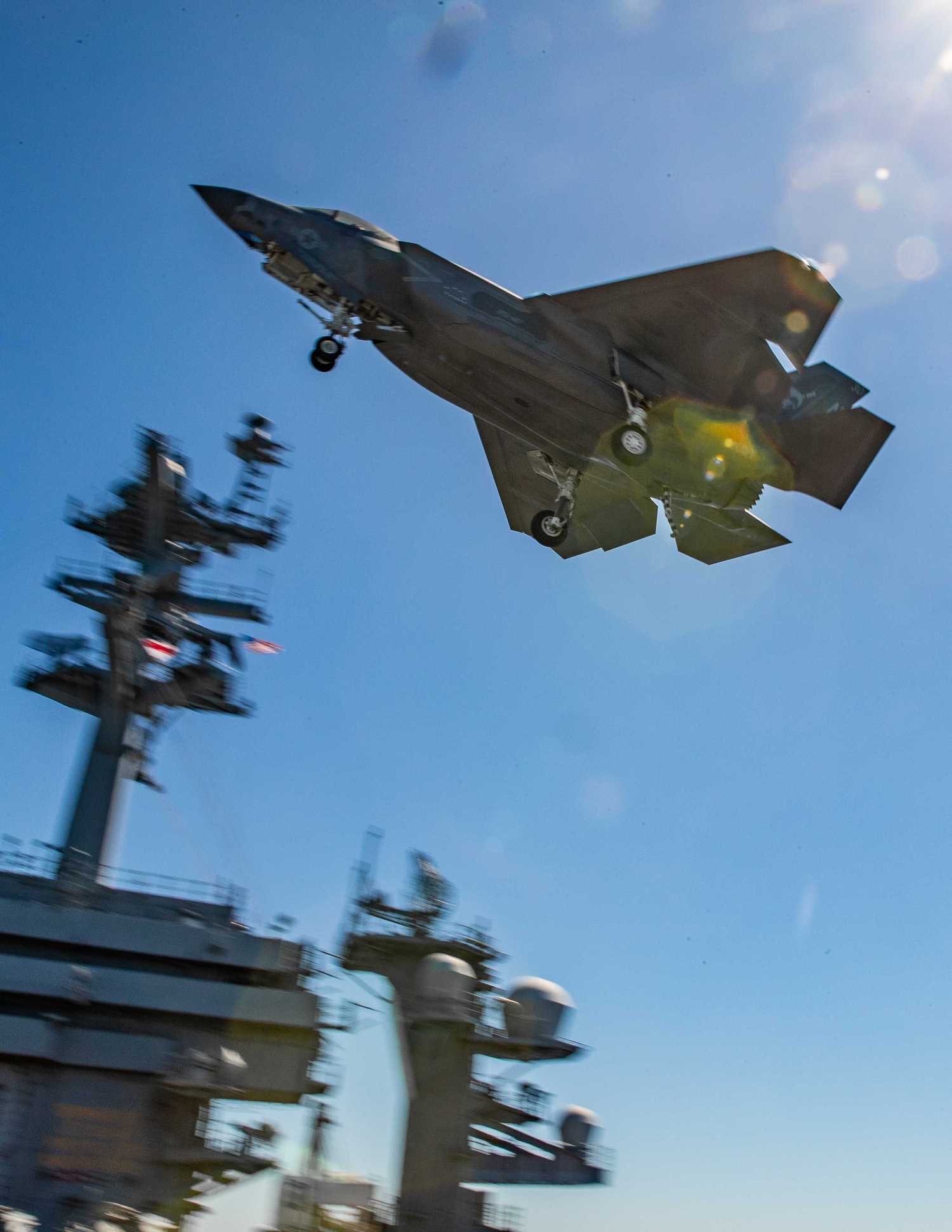 An F35C Lightning II, attached to Strike Fighter Squadron (VFA) 147, flies over the flight deck.