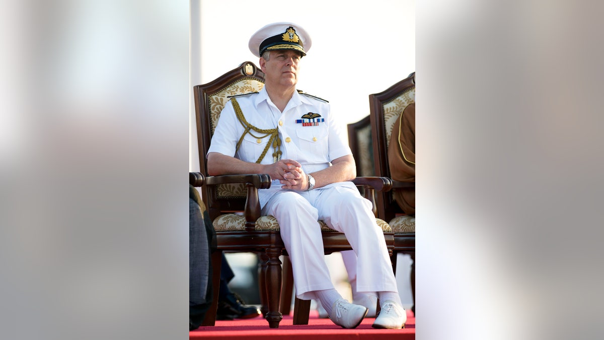 Andrew in a white Navy uniform sitting down looking pensive.