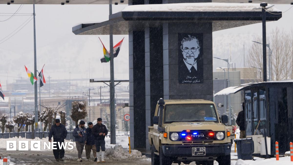 Scene at Iraqi border with Iran, as a vehicle and people pass through a crossing point in the snow