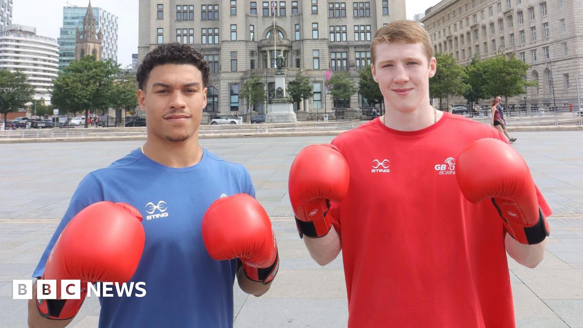 Odel Kamara and Callum Makin posing with their boxing gloves. Odel has short curly, dark hair and is wearing a blue top, and Callim has short light-brown hair and is wearing a red top.