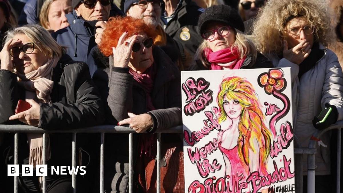 Crowds gather for the funeral of French film icon Brigitte Bardot in Saint-Tropez, southern France. One woman is seen holding a picture of the actress. Photo: 7 January 2026