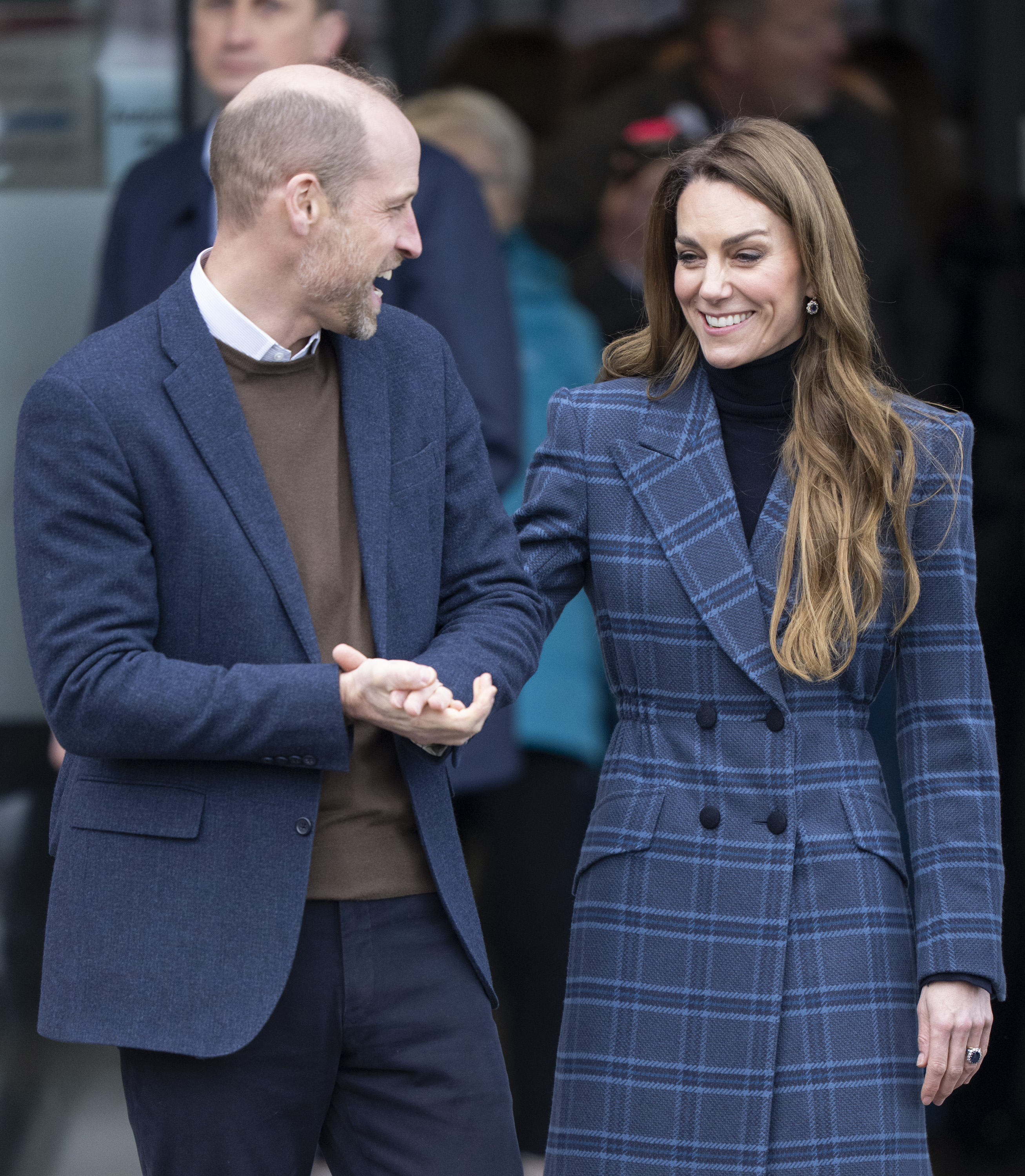 Prince William and Princess Kate wearing blue jackets and laughing