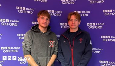 Identical twins Chris and Johnny standing in front of a purple BBC branded background.