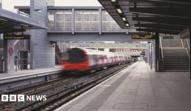 Platform at Stratford station shows departing Jubilee line train on left with bridge ahead and steps to the right. A departure board shows Waterloo