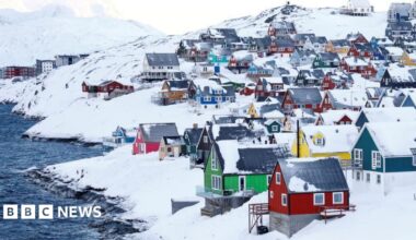 Colourful little houses stand amid lots of snow next to some water