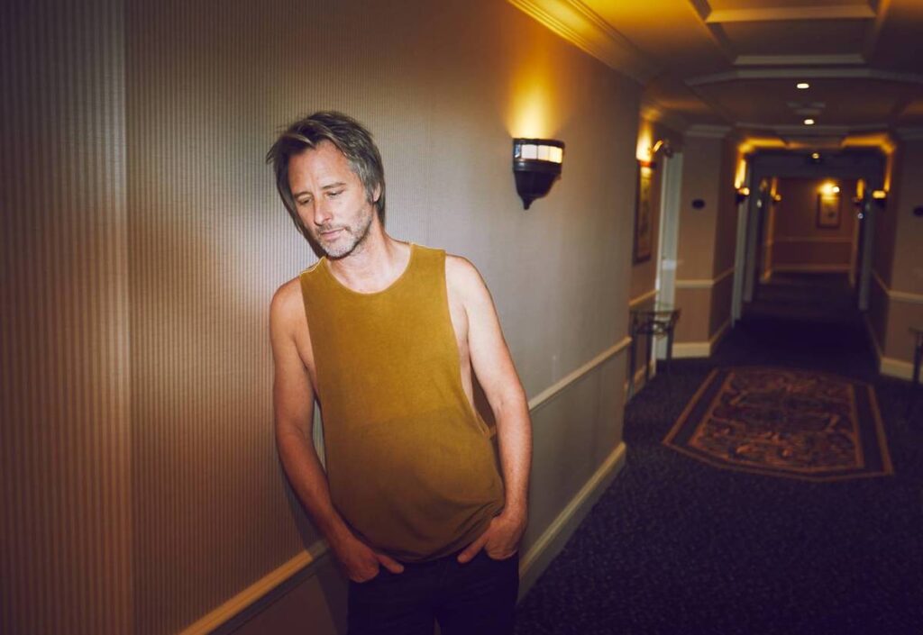 chesney hawkes in hotel hallway wearing mustard yellow vest