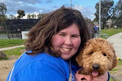 A young girl smiles while holding a dog