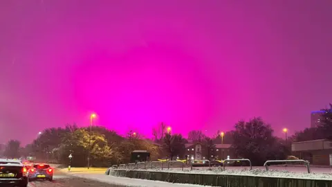 A bright pink sky over a snowy Birmingham road