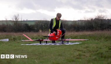 A man wearing a hi vis vest assembles a drone at an airfield in Oxfordshire