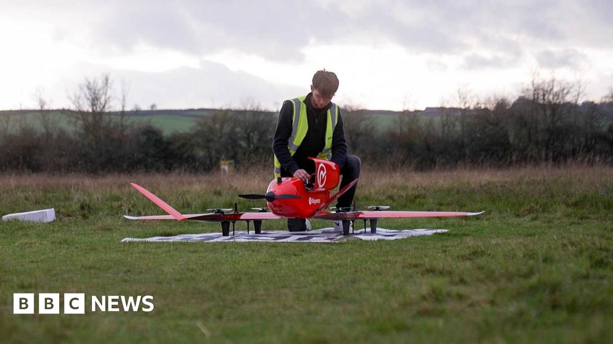 A man wearing a hi vis vest assembles a drone at an airfield in Oxfordshire