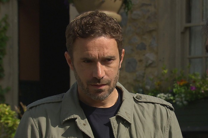 Oliver Farnworth as John Sugden in Emmerdale in close-up looking stern.