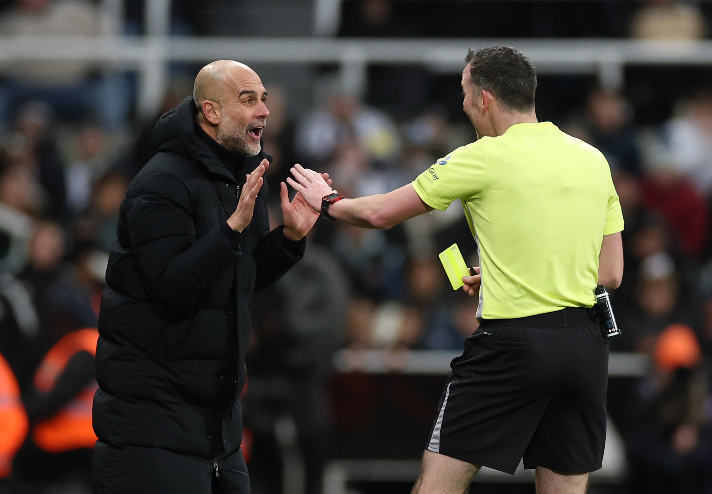 NEWCASTLE UPON TYNE, ENGLAND - JANUARY 13: Pep Guardiola, Manager of Manchester City, interacts with referee Chris Kavanagh after a member of his coaching staff was shown a yellow card during the Carabao Cup Semi Final First Leg match between Newcastle United and Manchester City at St James’ Park on January 13, 2026 in Newcastle upon Tyne, England. (Photo by Stu Forster/Getty Images)