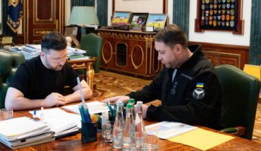 Volodymyr Zelensky and Kyrylo Budanov sit at a desk in an official office, reviewing documents together.