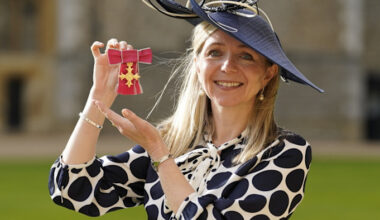 Dr Melanie Ivarsson smiles and holds up her OBE medal after an investiture ceremony at Windsor Castle.