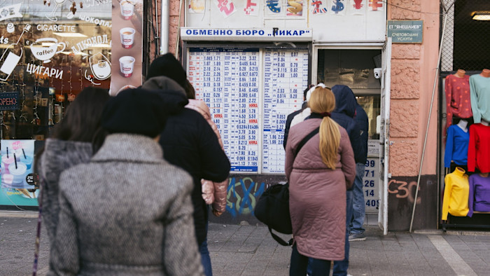 People stand in line at a currency exchange displaying rates in Sofia, Bulgaria, ahead of the euro’s adoption.