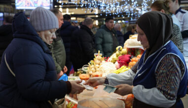 A customer hands Russian rouble banknotes to a vendor at a produce stall in a decorated food market in Moscow.
