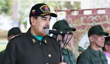 Nicolas Maduro, wearing a military uniform and cap, speaks into a microphone during an event with Venezuelan military personnel.