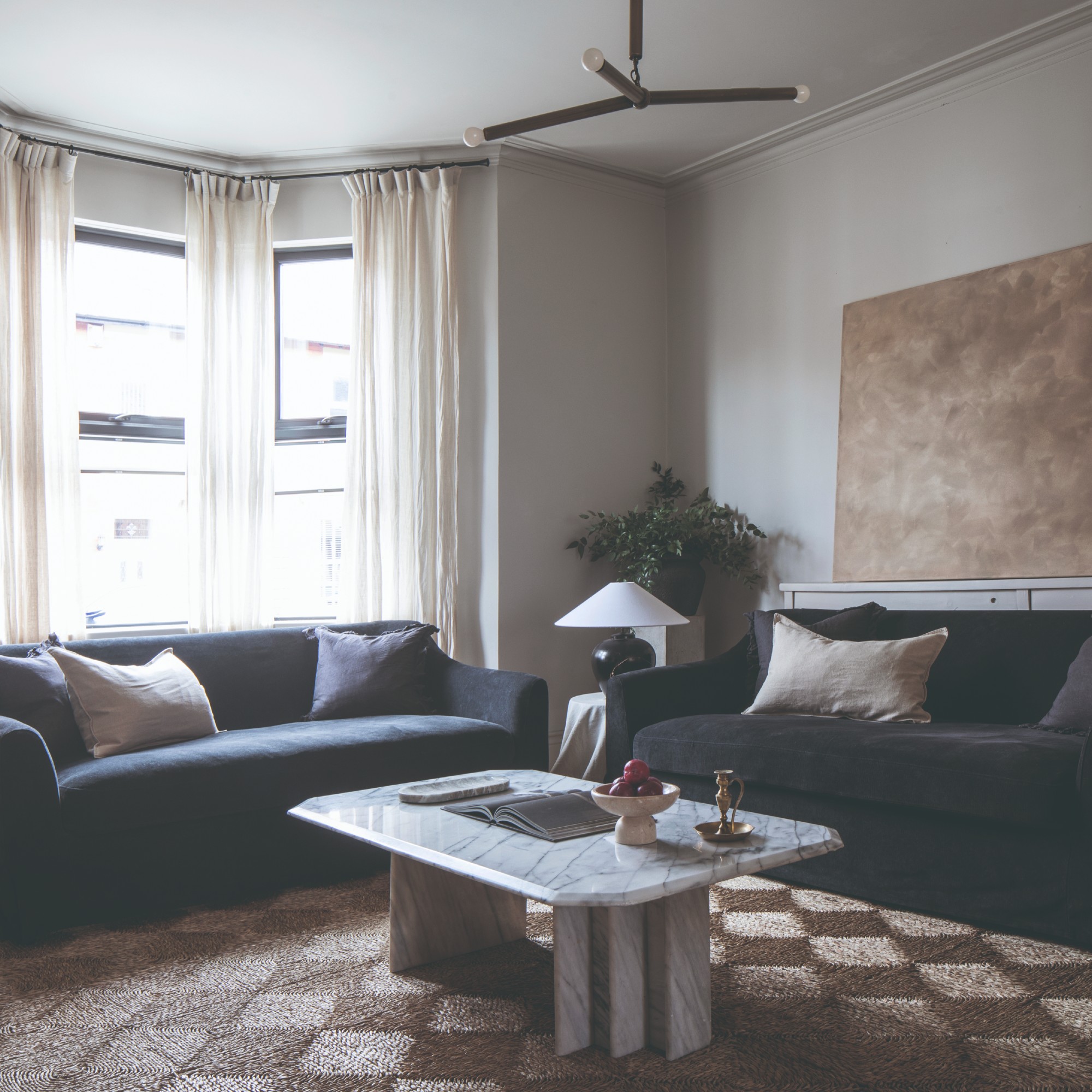 A living room with two dark sofas, a marble coffee table and a jute rug