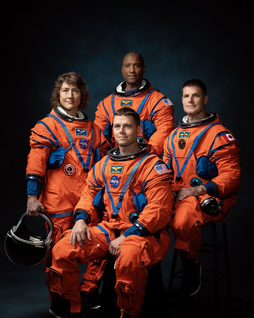 NASA astronauts Reid Wiseman, Victor Glover, and Christina Hammock Koch, and CSA astronaut Jeremy Hansen pose in their orange flight suits for a photo.