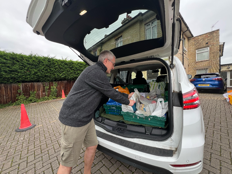 A man unloading containers of food from the boot of a car