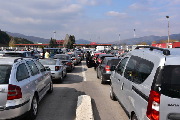 Cars queue at a border crossing checkpoint, filling multiple lanes as drivers wait to pass inspection.