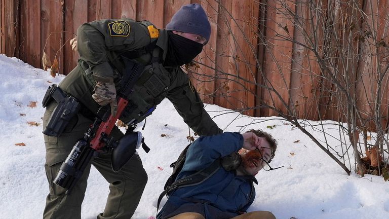 A member of  Immigration and Customs Enforcement (ICE) restrains a protester trying to block vehicles from leaving the scene.
Pic: Reuters