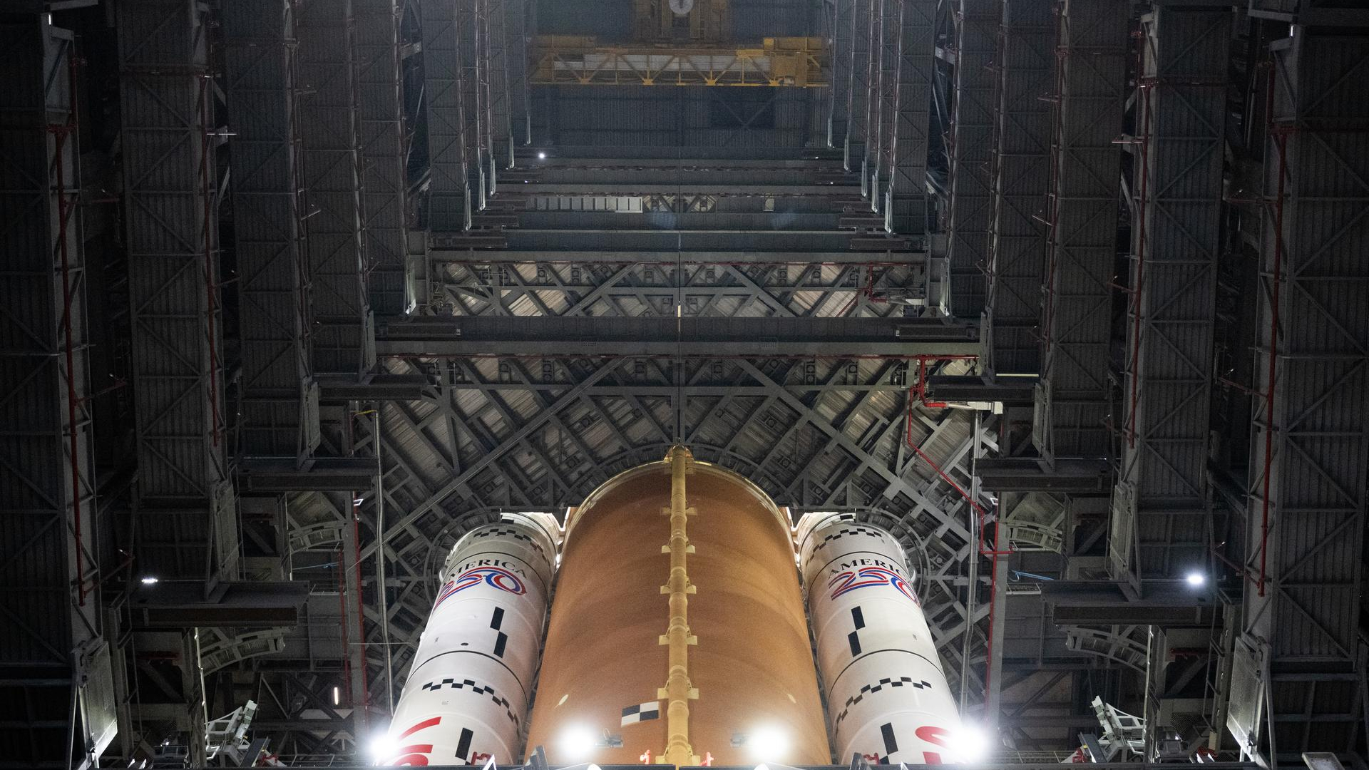 A large rocket is lit up looking up into a large warehouse.
