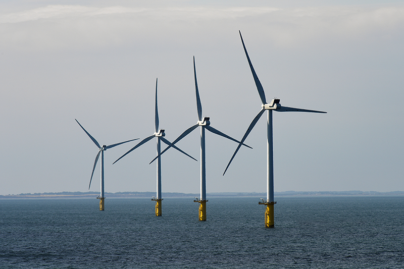 Stock image of four wind turbines in a row in the North Sea