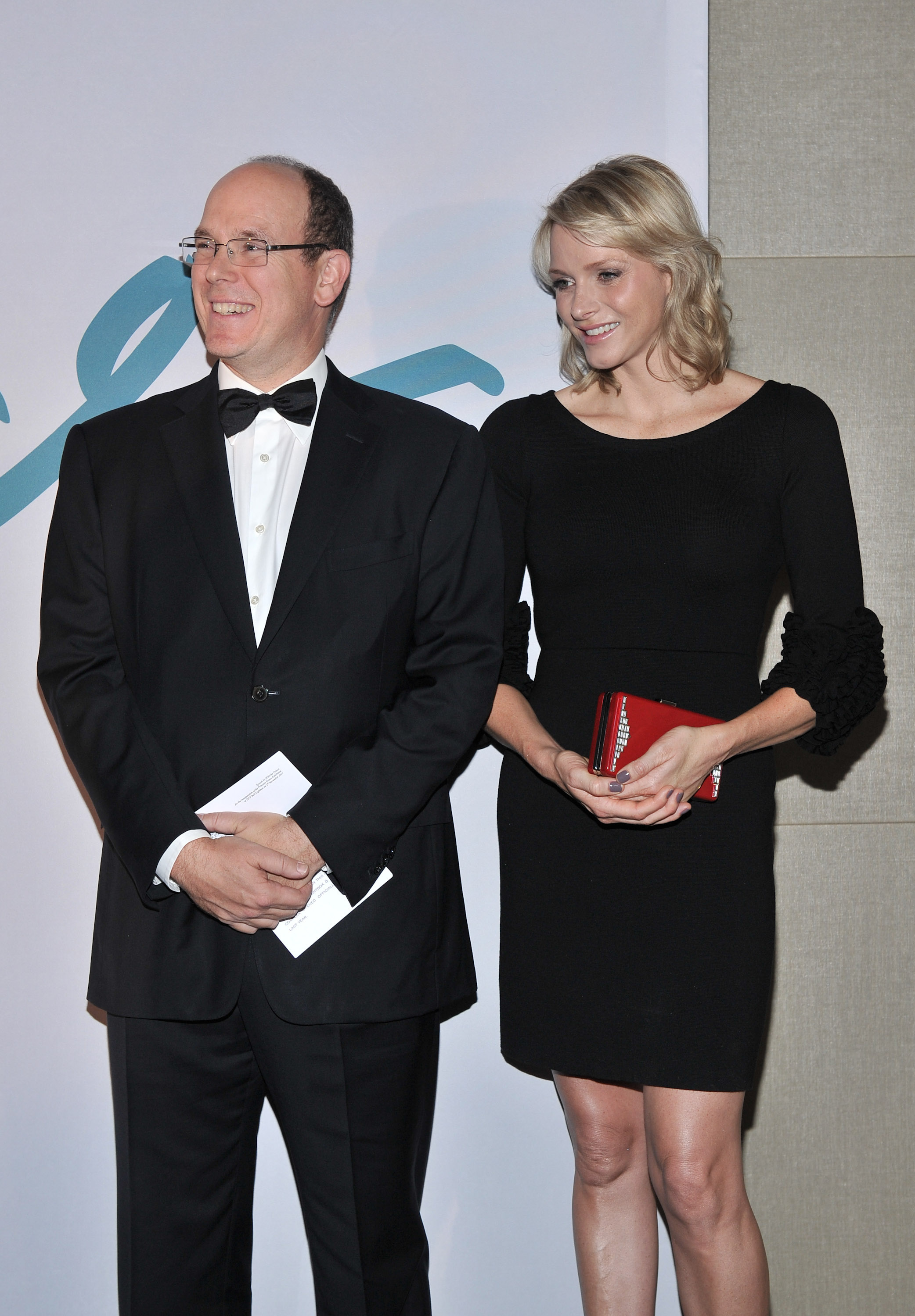 Princess Charlene wearing a black dress in 2011 standing next to Prince Albert, wearing a tux