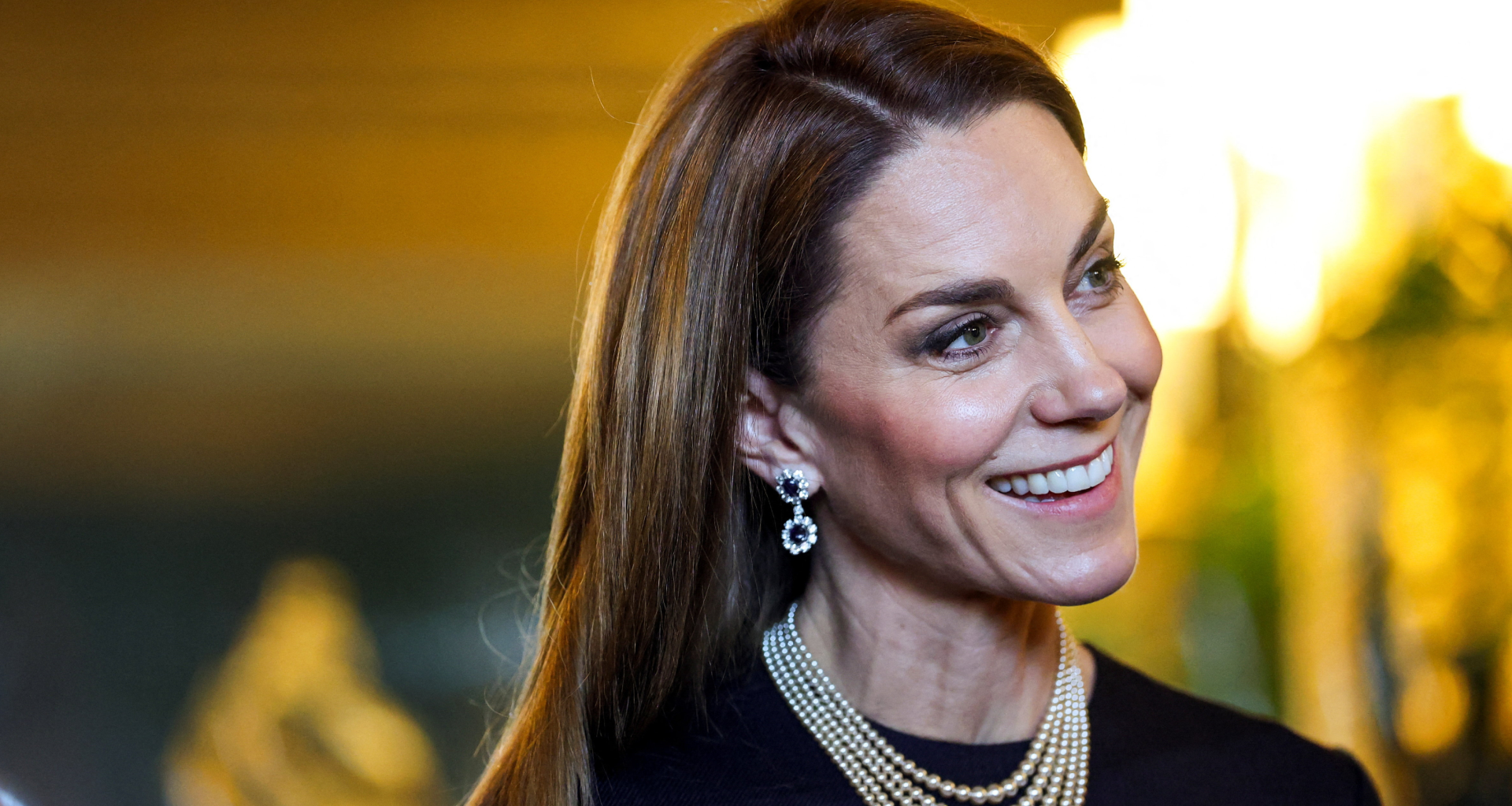 Princess Kate wearing a pearl necklace and sapphire earrings and smiling