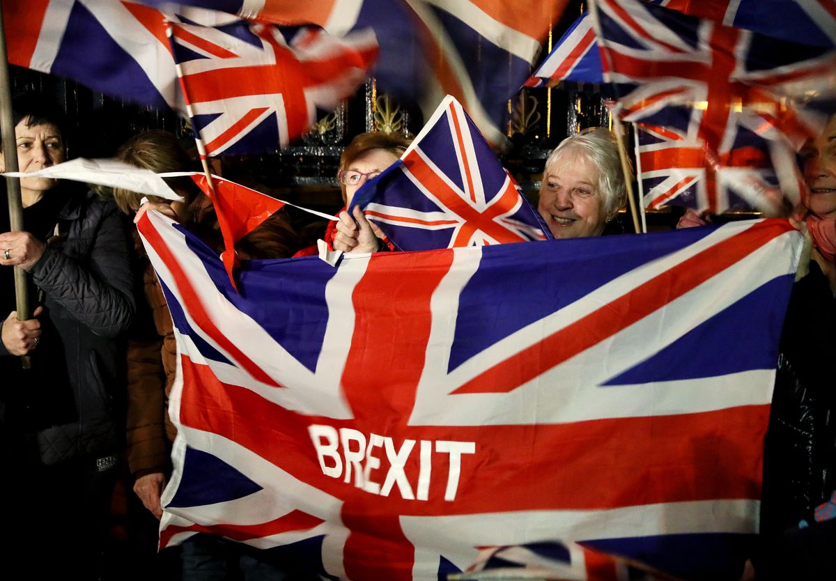 Pro-Brexit supporters gather to celebrate outside Stormont in Belfast holding Union Jack flags with 'BREXIT' across them
