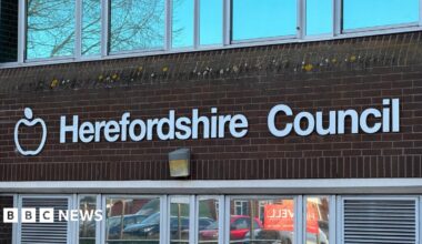 A red brick building with white letting reading "Herefordshire Council".