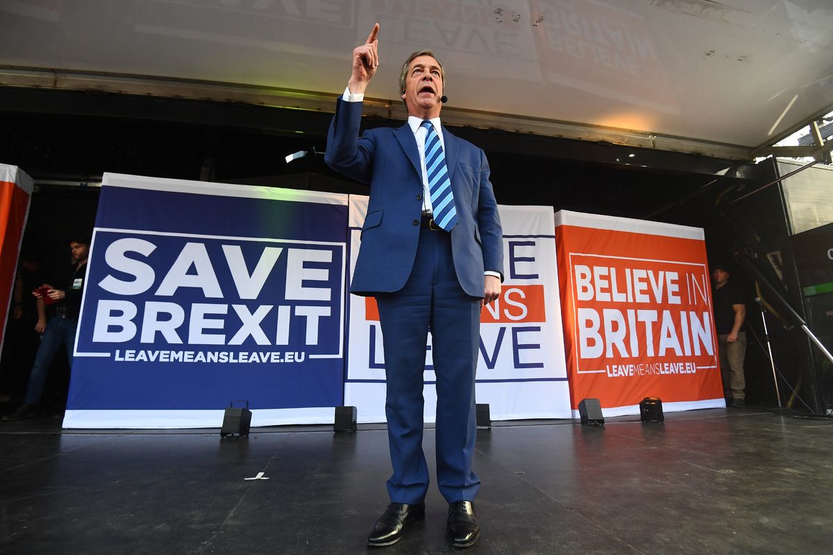 Nigel Farage stood on stage speaking to protesters in front of banners reading 'SAVE BREXIT' and 'BELIEVE IN BRITAIN'