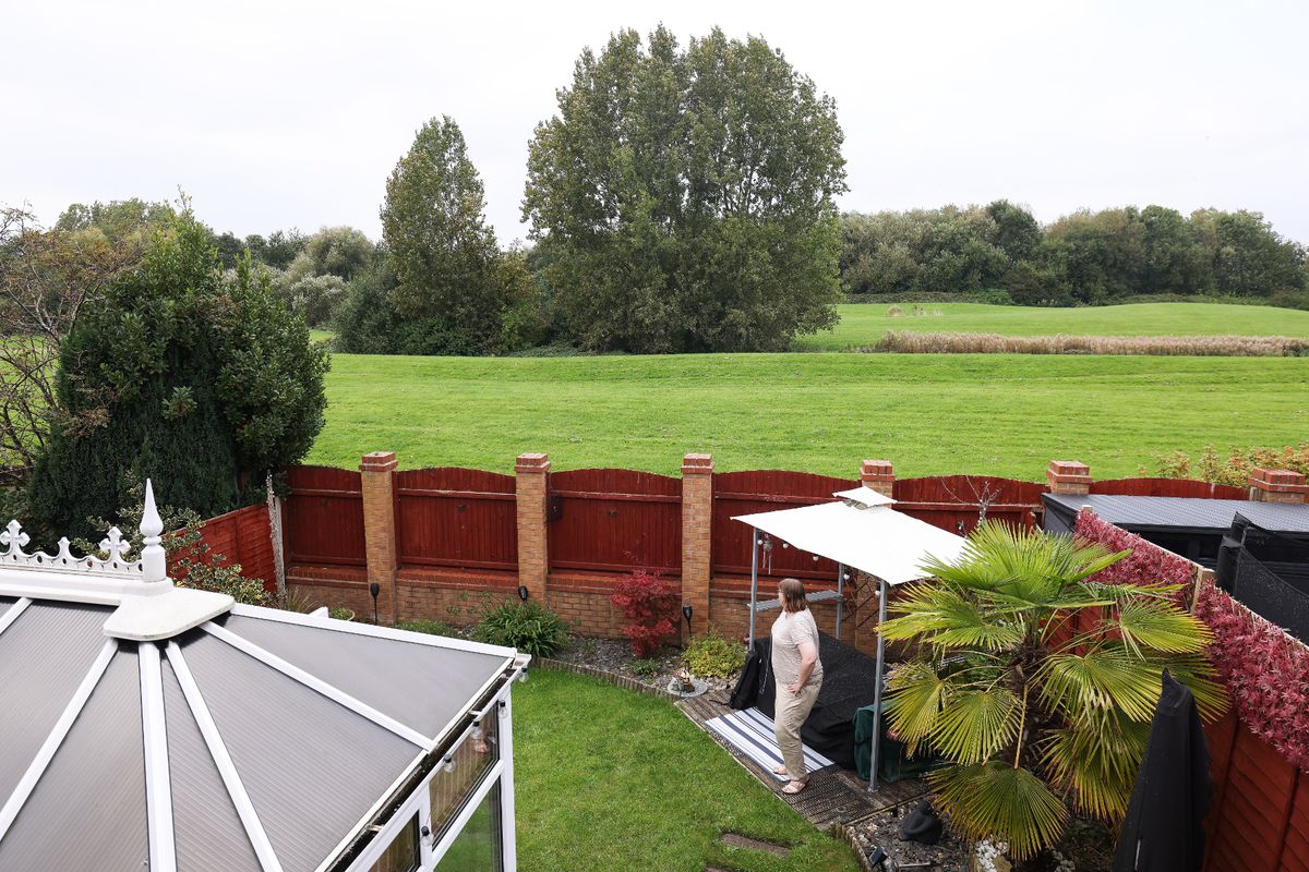 A resident looks out from a property on Whinberry Drive in Kirkby 2024, with proposed development site on other side of fence