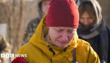 Roman, a Ukrainian soldier in a drone repair unit, holds up an unmanned aerial vehicle and faces the camera. He's in his green army uniform.