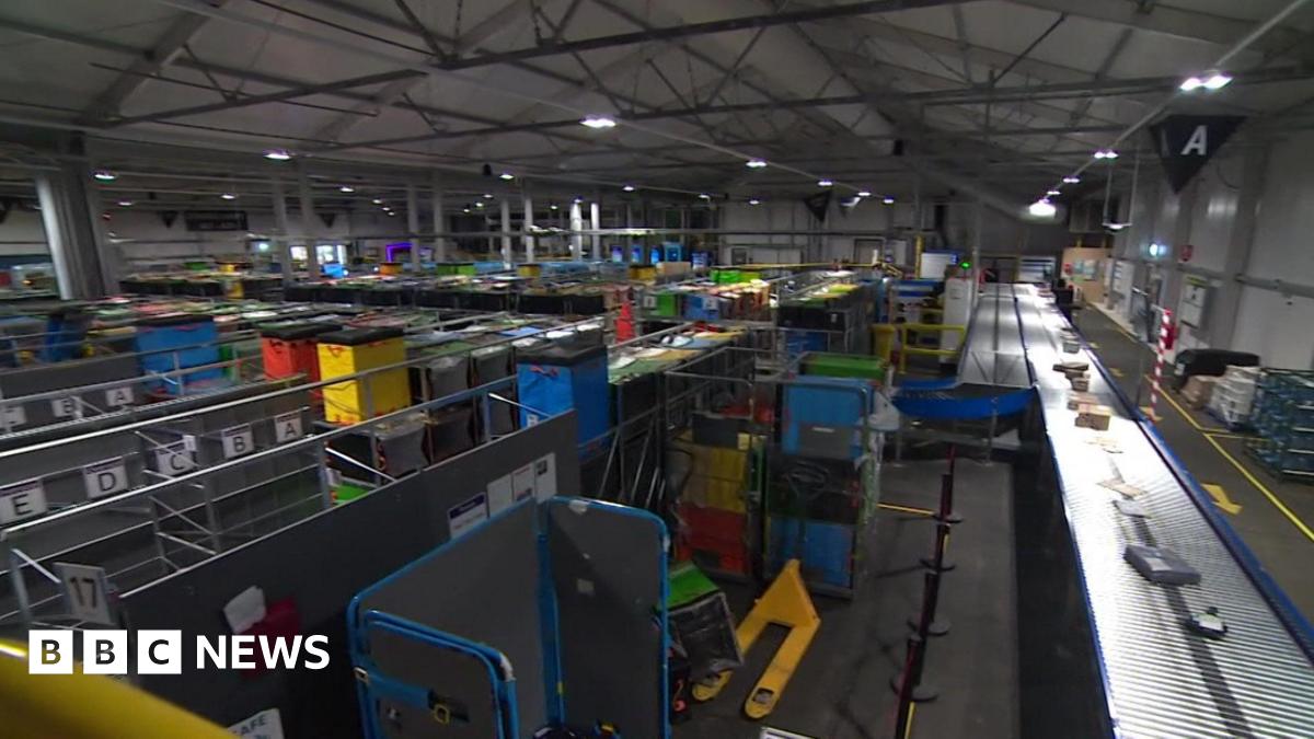 A view inside the Amazon warehouse showing large metal shelving and conveyor belts.