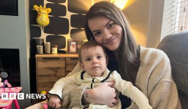 Leah Cullen, who has long dark hair and dressed in a cream cardigan, sits with her daughter Aria on her lap in their home in Blyth.