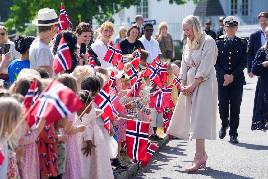 A woman speaking to a large crowd of people, many whom are waving small flags.