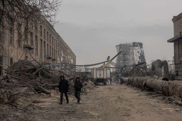 Employees walk past sections of the Darnytska combined heat and power plant damaged by Russian air strikes as they work onn its repair in Kyiv, on February 4, 2026, amid the Russian invasion of Ukraine. Recent Russian strikes on Ukraine's power infrastructure have disrupted light, heating and water supplies to millions across the country as temperatures plummet well below freezing, leaving the war-battered country facing a fresh humanitarian crisis. (Photo by Roman PILIPEY / AFP)