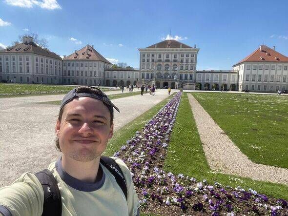 Man takes a selfie in front of a German palace on a sunny day