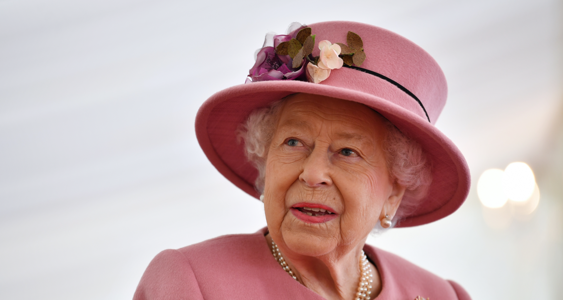Queen Elizabeth wearing a pink hat and coat looking to the side