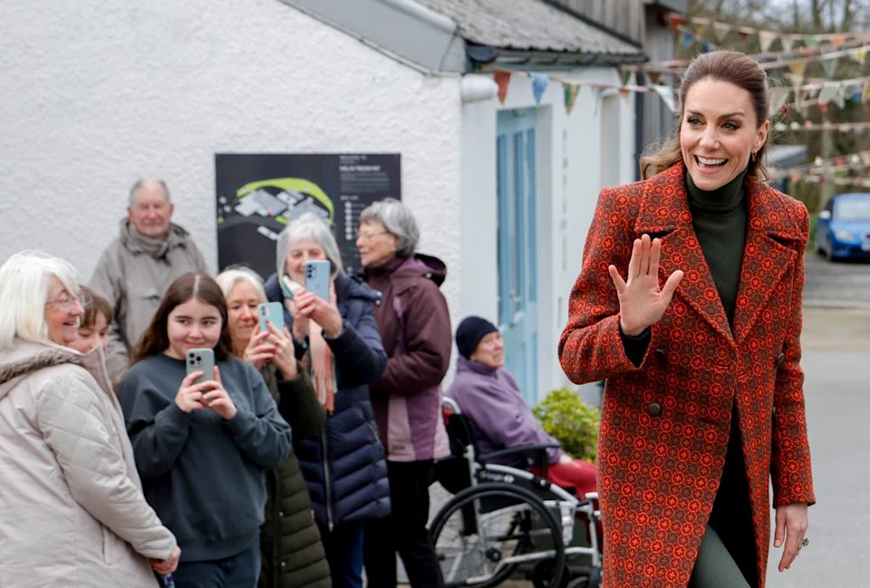Kate Middleton waving to fans in front of a white building