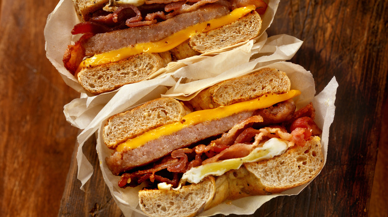 Bacon Egg and cheese on a bagel in white paper on wooden table